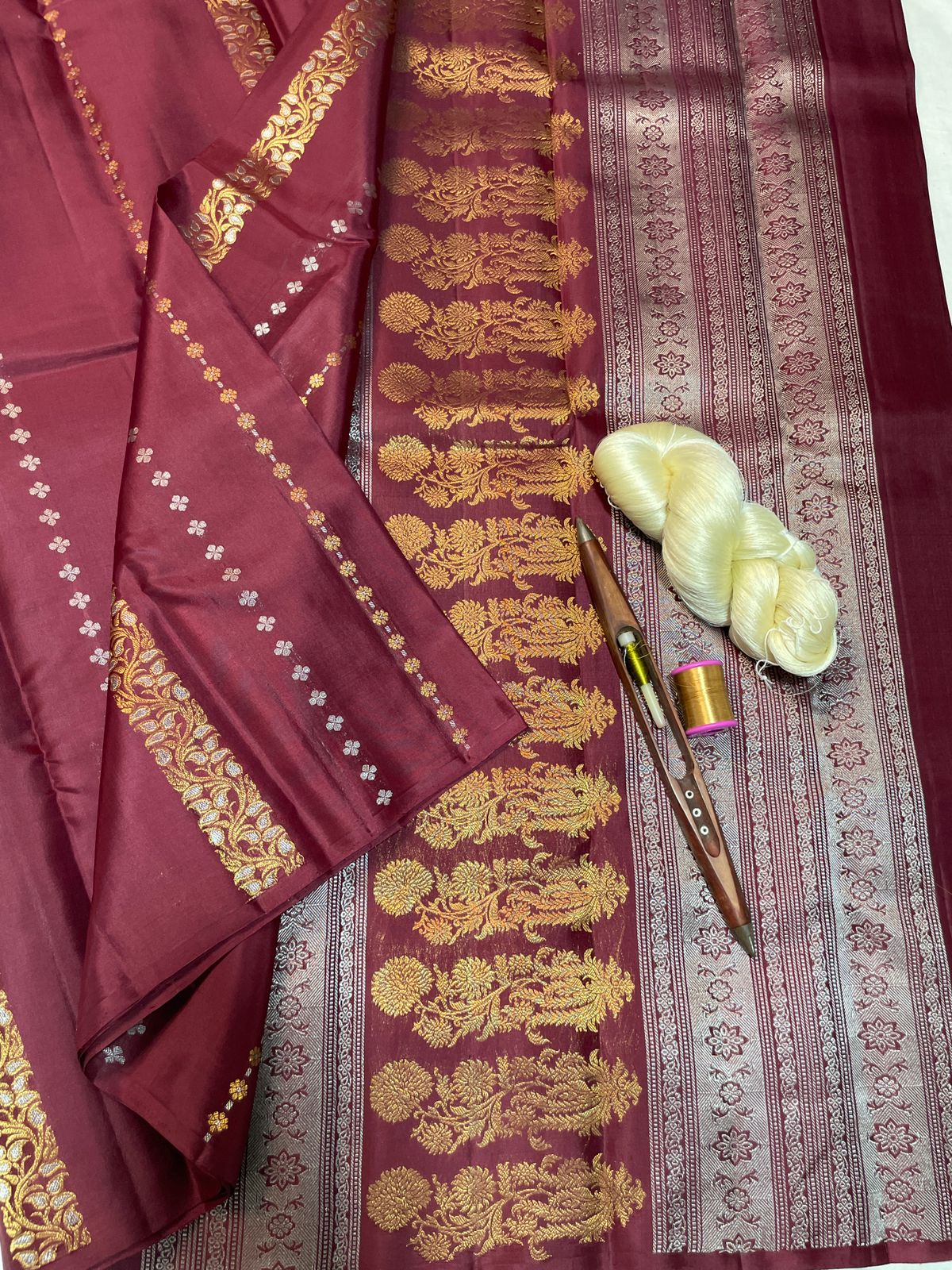 Maroon saree with gold embroidery on a textured surface